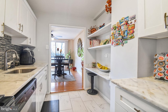 kitchen with sink, backsplash, light stone counters, white cabinetry, and dishwasher