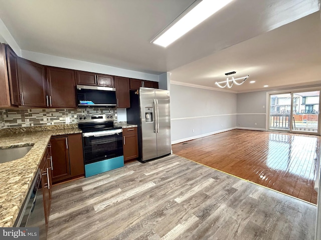 kitchen with light wood finished floors, tasteful backsplash, appliances with stainless steel finishes, ornamental molding, and light stone countertops