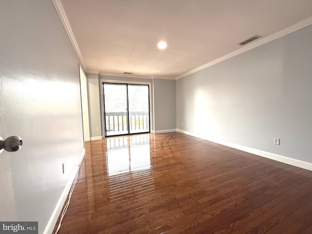 empty room with ornamental molding, wood finished floors, and visible vents