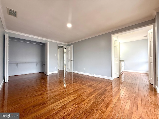 unfurnished bedroom with visible vents, baseboards, a closet, hardwood / wood-style floors, and crown molding