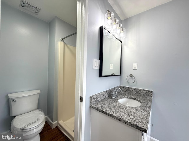 bathroom featuring visible vents, toilet, wood finished floors, vanity, and a shower stall