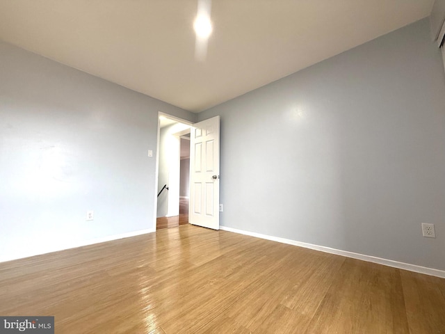 spare room with baseboards and light wood finished floors