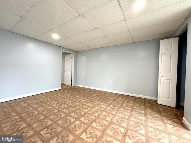 finished below grade area featuring a paneled ceiling and baseboards