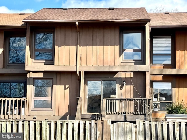 exterior space with a shingled roof and fence