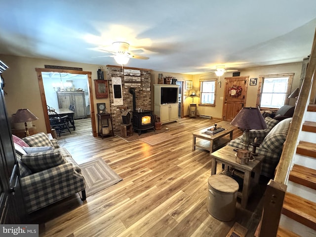 living room with ceiling fan, light hardwood / wood-style floors, and a wood stove