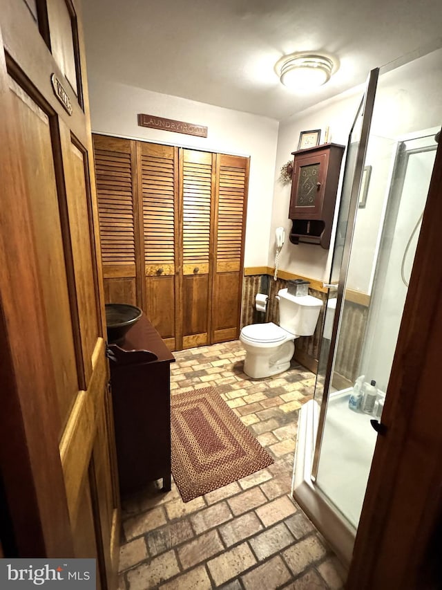 bathroom with a shower with door, vanity, and toilet