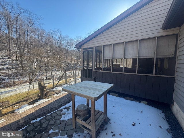 snow covered patio with a sunroom