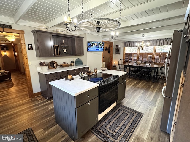 kitchen with dark brown cabinetry, black electric range oven, a chandelier, hanging light fixtures, and a kitchen island with sink