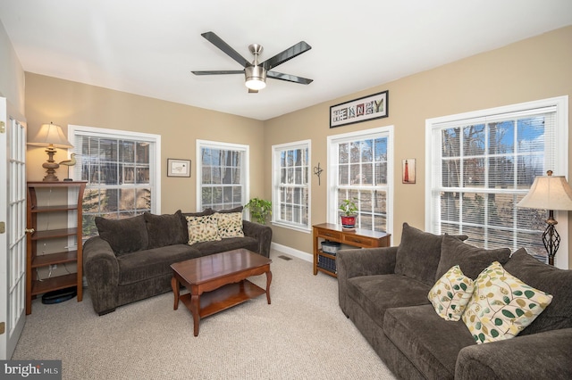 living room featuring light carpet, ceiling fan, visible vents, and baseboards