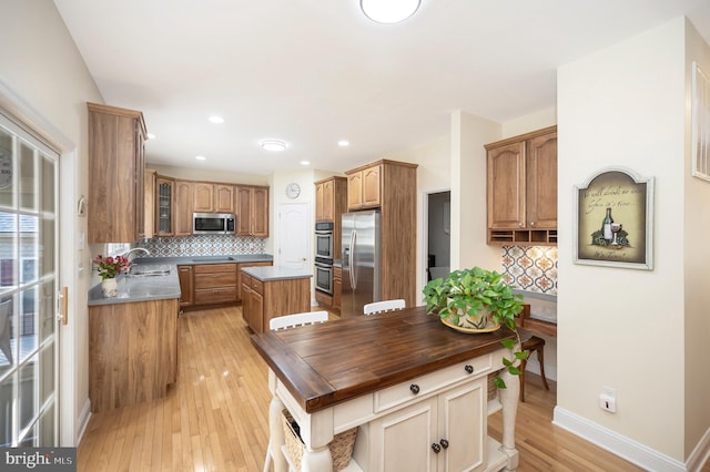 kitchen with a center island, stainless steel appliances, decorative backsplash, glass insert cabinets, and a sink