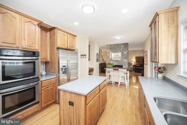 kitchen with open floor plan, a center island, stainless steel appliances, light countertops, and light wood-style floors