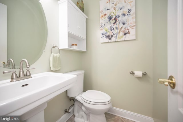 half bathroom featuring baseboards, a sink, and toilet