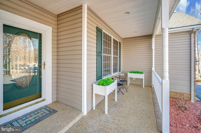 view of exterior entry with a porch and a shingled roof