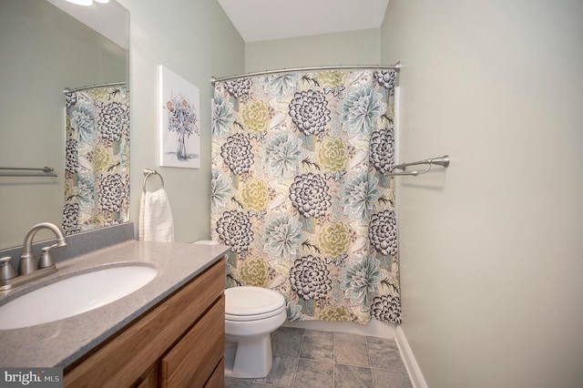 bathroom featuring toilet, baseboards, a shower with shower curtain, and vanity