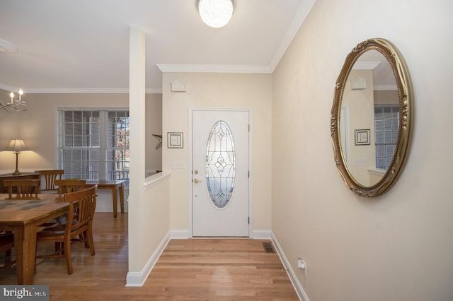 foyer entrance with light wood finished floors, baseboards, visible vents, and crown molding