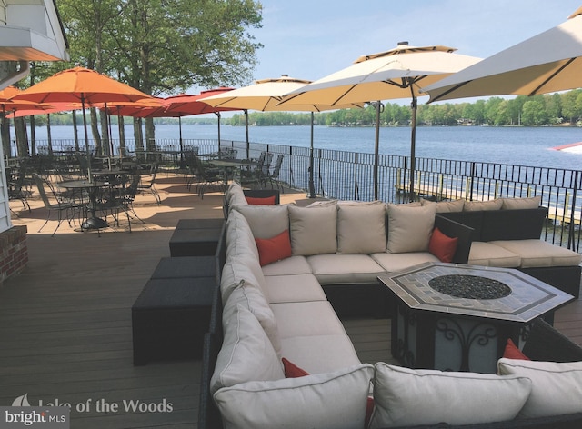 view of patio / terrace featuring outdoor dining space, an outdoor living space with a fire pit, fence, and a water view