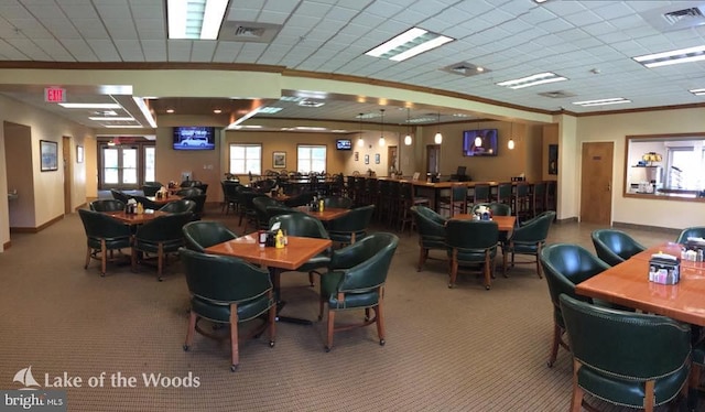 carpeted dining area with a paneled ceiling, baseboards, visible vents, and ornamental molding