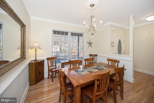 dining room with ornamental molding, light wood finished floors, baseboards, and an inviting chandelier