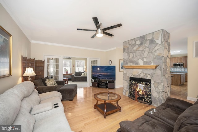 living area featuring ornamental molding, ceiling fan, light wood finished floors, and a fireplace