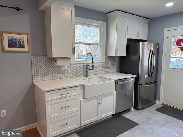 kitchen featuring appliances with stainless steel finishes, light countertops, a sink, and tasteful backsplash