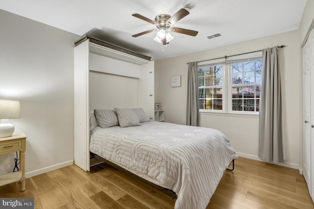 bedroom featuring a ceiling fan, baseboards, visible vents, and wood finished floors