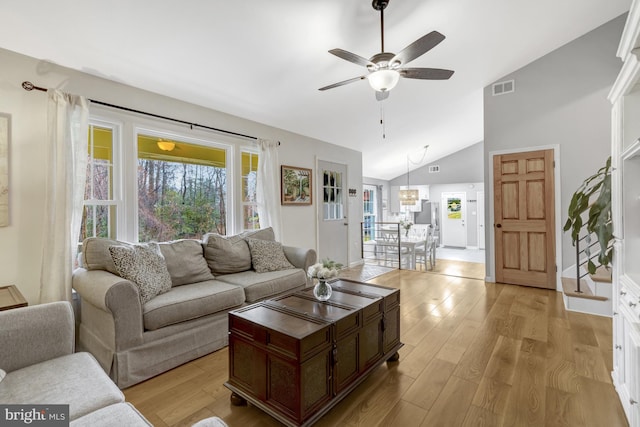 living area featuring high vaulted ceiling, visible vents, ceiling fan, and light wood finished floors