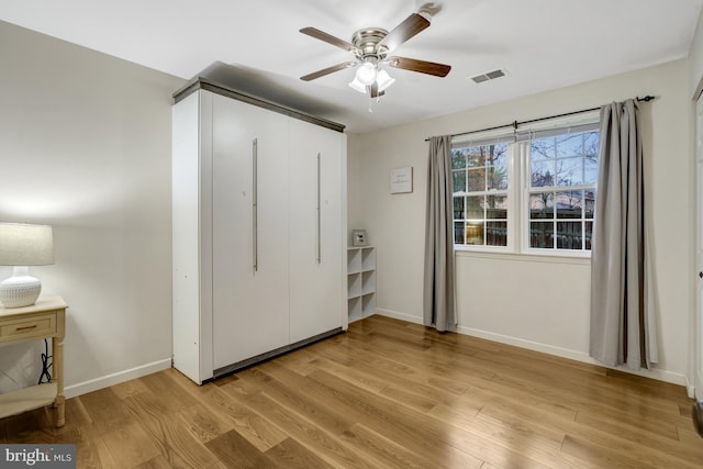 unfurnished bedroom with light wood-style flooring, a ceiling fan, visible vents, baseboards, and a closet