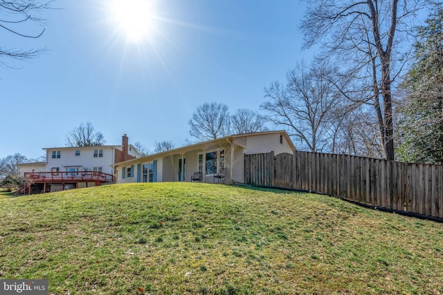 back of house with a gate, fence, a deck, and a lawn