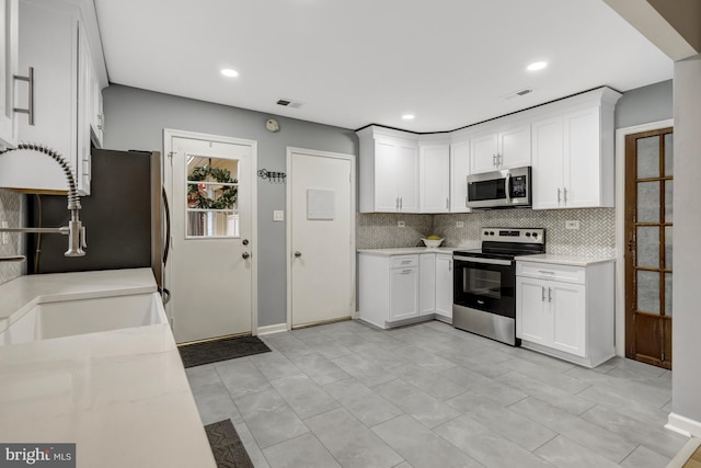 kitchen featuring stainless steel appliances, light countertops, visible vents, and tasteful backsplash