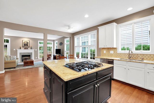 kitchen with sink, light hardwood / wood-style flooring, stainless steel appliances, white cabinets, and a kitchen island