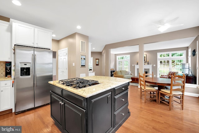 kitchen with white cabinetry, appliances with stainless steel finishes, a center island, and light hardwood / wood-style flooring