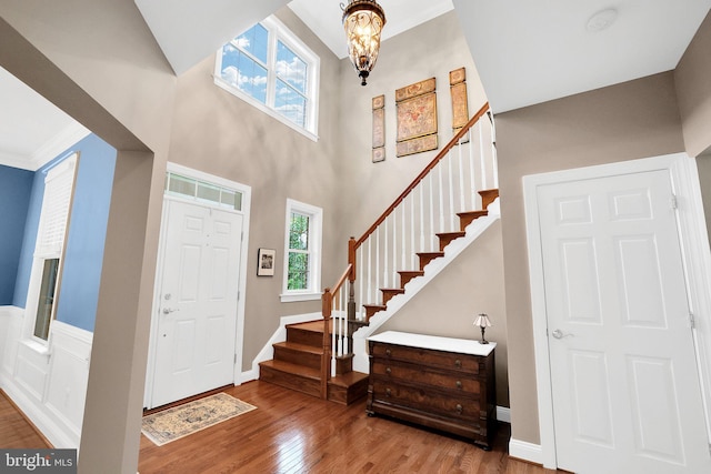 entrance foyer featuring wood-type flooring, a towering ceiling, and a notable chandelier