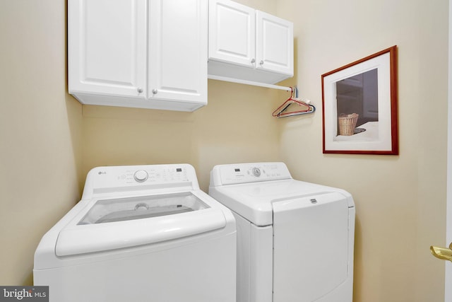 clothes washing area with cabinets and washer and dryer