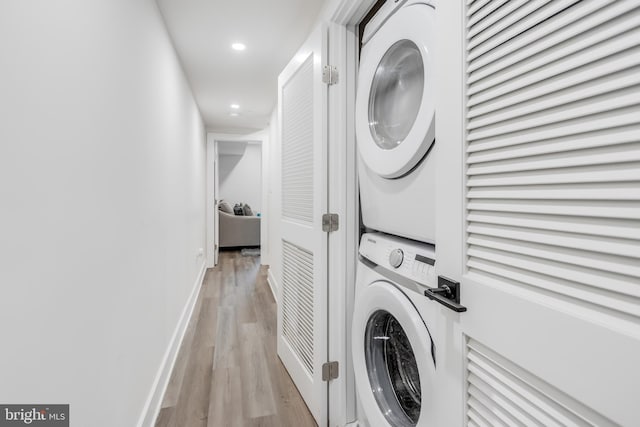 laundry room with light wood-type flooring and stacked washing maching and dryer