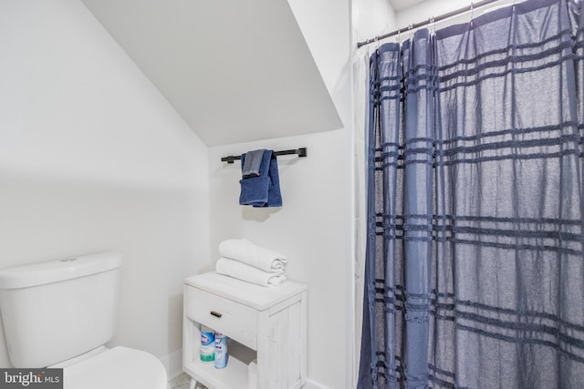 bathroom with toilet, curtained shower, and vaulted ceiling