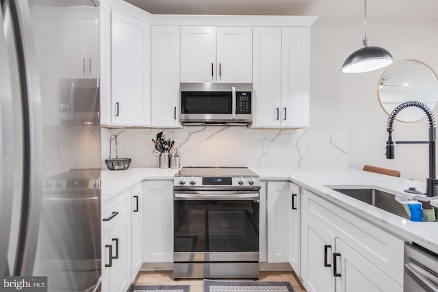 kitchen featuring pendant lighting, sink, white cabinets, and appliances with stainless steel finishes