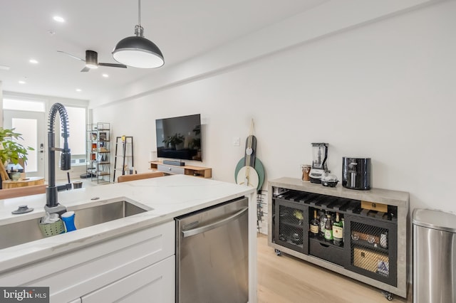 kitchen featuring sink, white cabinetry, light stone counters, decorative light fixtures, and stainless steel dishwasher