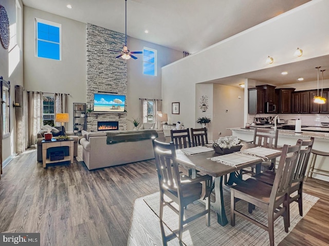 dining space featuring wood-type flooring, ceiling fan, and a fireplace