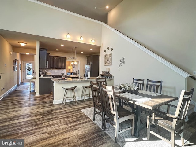 dining room with sink, ornamental molding, dark hardwood / wood-style floors, and a high ceiling