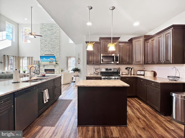 kitchen with sink, dark brown cabinets, a kitchen island, pendant lighting, and stainless steel appliances