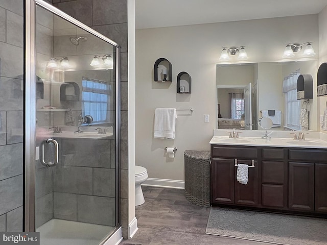 bathroom featuring a shower with door, vanity, hardwood / wood-style floors, and toilet