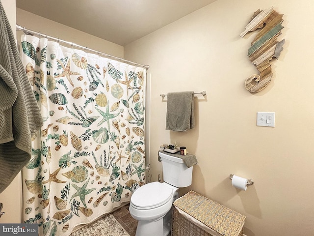 bathroom with curtained shower, tile patterned floors, and toilet