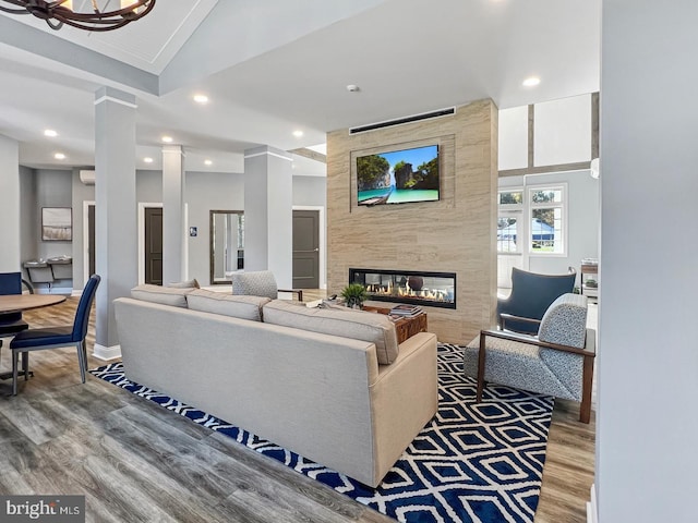 living room with lofted ceiling, hardwood / wood-style flooring, a fireplace, and decorative columns