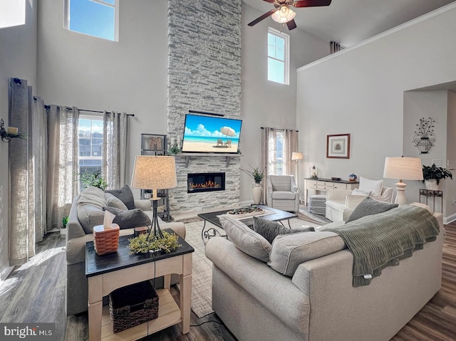 living room featuring hardwood / wood-style flooring, ceiling fan, a stone fireplace, and a wealth of natural light