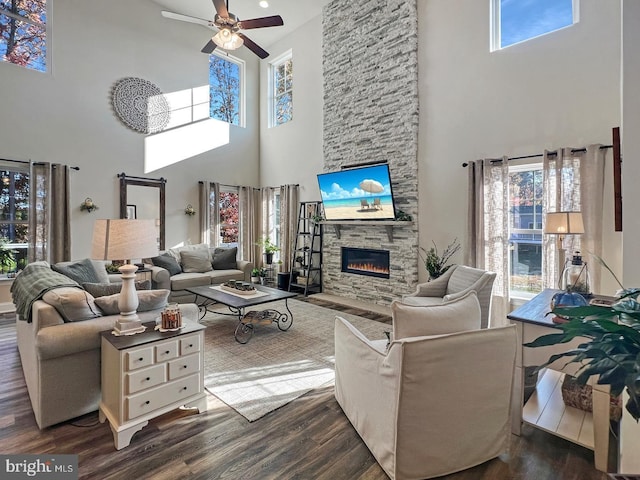 living room with a fireplace, dark wood-type flooring, and ceiling fan