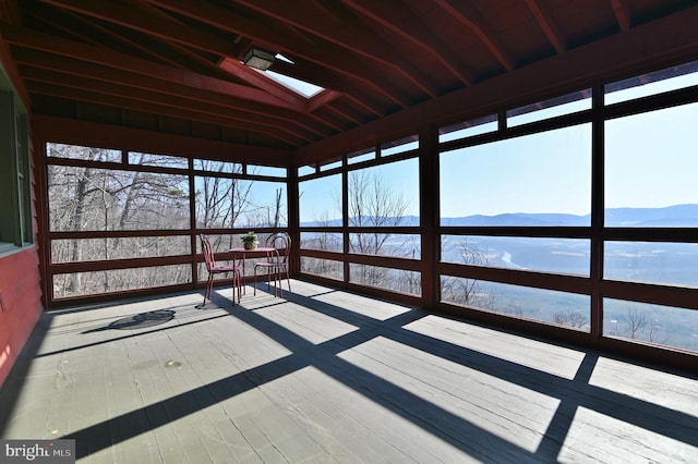 unfurnished sunroom featuring lofted ceiling with skylight and a mountain view