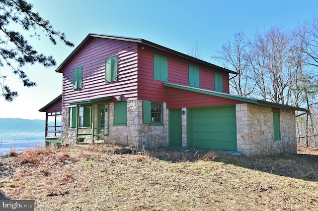 view of front of house featuring a mountain view, stone siding, and an attached garage