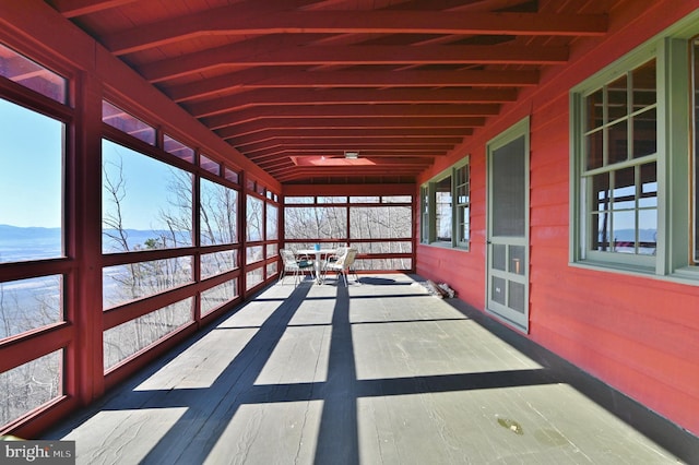 unfurnished sunroom featuring vaulted ceiling with beams