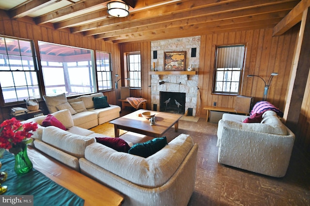 living room with a wealth of natural light, beam ceiling, wooden walls, and a fireplace