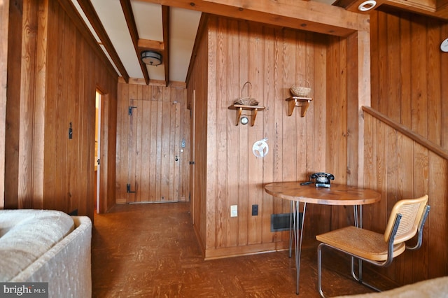 interior space featuring beam ceiling and wooden walls